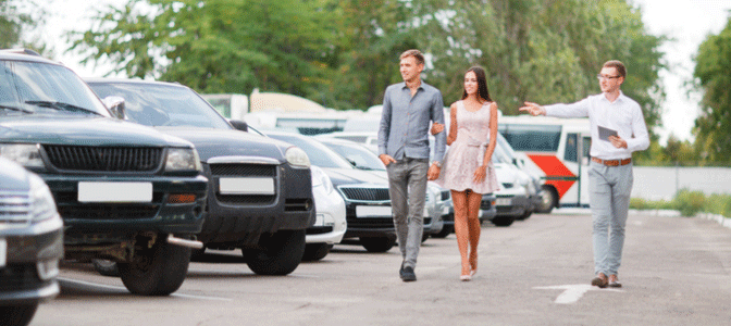 A couple walking in a car lot trying to buy a car despite having student loan debt